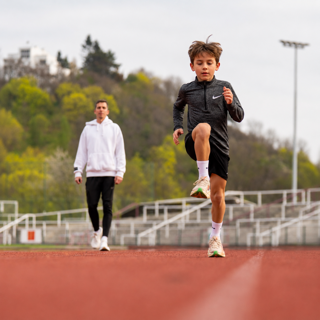 Trenér instruuje dítě na atletické dráze